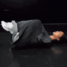 a woman in a black shirt is laying on the floor with her legs crossed