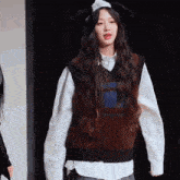 a girl wearing a vest and a white shirt has the number 9 on her shirt
