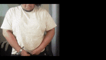 a man wearing a white t-shirt is standing with his hands behind his back