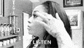 a black and white photo of a woman covering her face with her hand and the words `` listen '' written on the bottom .