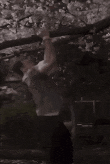 a person is hanging from a tree branch with flowers on it .