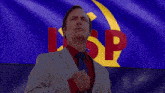a man in a suit and tie stands in front of a flag with the letter sp on it