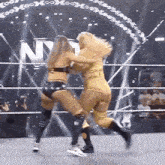 two women are wrestling in a wrestling ring and one of them is wearing a yellow outfit .