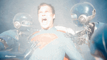 a man in a superman suit is surrounded by robots