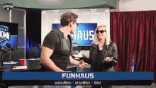 a man and a woman are standing in front of a sign that says funhaus