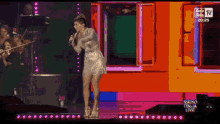 a woman singing into a microphone on a stage with the words radio italia live written on the bottom