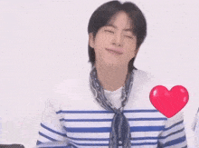 a man wearing a blue and white striped shirt with a scarf around his neck and a red heart on his chest
