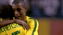 a man in a yellow shirt with the name peterson on it hugging another man