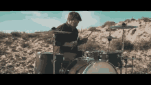 a man is playing a drum set in the middle of a desert