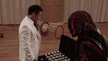 a man in a white suit stands next to a robot in a black suit