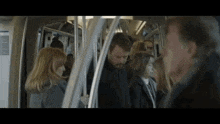 a group of people are riding a subway train and talking to each other .