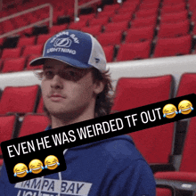 a man wearing a tampa bay lightning hat is sitting in a stadium