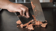 a person is cutting meat with a spatula and knife