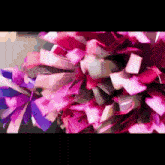 a bunch of pink and purple pom poms are flying in the air