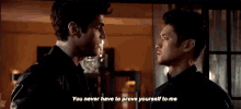 two men are standing next to each other in a room and talking to each other .