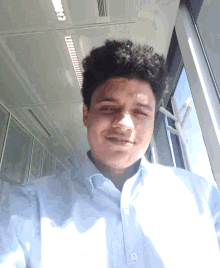 a young man in a light blue shirt smiles for the camera