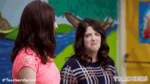 two women are standing next to each other in front of a painting of a moose .