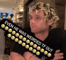 a man with curly hair is sitting at a table with a sticker that says even he was weirded tf out