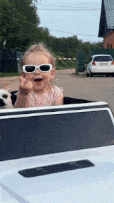 a little girl wearing sunglasses is giving the middle finger while sitting in a car