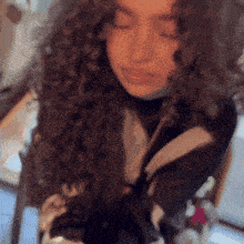 a woman with curly hair is wearing a black and white jacket