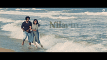 a man and a woman are walking on the beach with the word nilarin in the corner