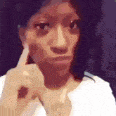 a woman in a white shirt is making a funny face with her finger on her ear