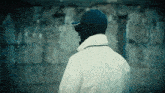 a man wearing a white jacket and a black hat with the letter a on it
