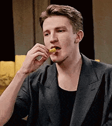 a man in a suit is eating a chicken nugget .