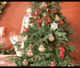 a woman is standing in front of a christmas tree