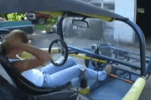 a man is sitting in the driver 's seat of a buggy while holding the steering wheel .