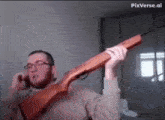 a man is talking on a cell phone while holding a rifle .