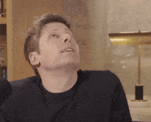 a man in a black sweater looks up at something