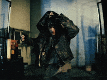 a man wearing a hooded jacket is standing in front of a telephone booth