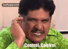 a man in a green shirt is making a funny face and says `` control control '' .