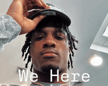 a man with dreadlocks is wearing a hat and the words we here are on his face