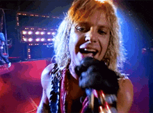 a man with blonde hair singing into a microphone