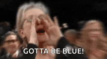 a woman is screaming in a crowd with her hands on her face and the words `` gotta be blue '' .