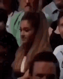 a woman is standing in a crowd of people looking at something .