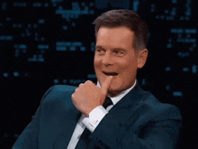 a man in a suit and tie is clapping his hands in the air