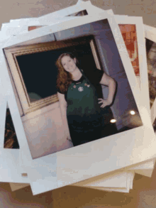 a woman in a green apron is standing in front of a framed picture