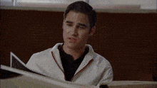 a man in a white jacket looks at a book