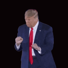 donald trump is wearing a suit and tie and making a fist