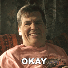 a man wearing a pink shirt with the word okay written on it