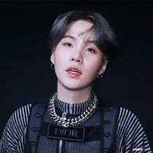 a close up of a person wearing a sweater , necklace , and earrings .