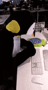 a person in a penguin costume is sitting at a desk