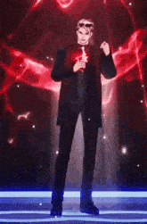 a man in a suit is standing on a stage holding a microphone and a red object .