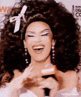 a woman in a wig is holding a microphone and smiling