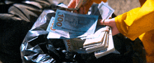 a person in a yellow jacket is holding a pile of 100 dollar bills