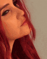 a close up of a woman 's face with red hair against a grey background
