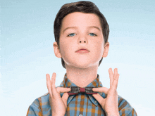 a young boy in a plaid shirt and bow tie